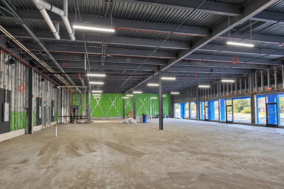 Open commercial interior with exposed structure and rows of overhead linear lighting