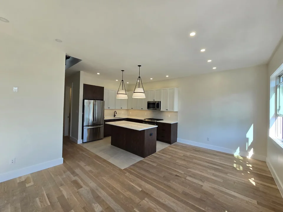 Residential kitchen and living space with recessed lighting and pendant fixtures
