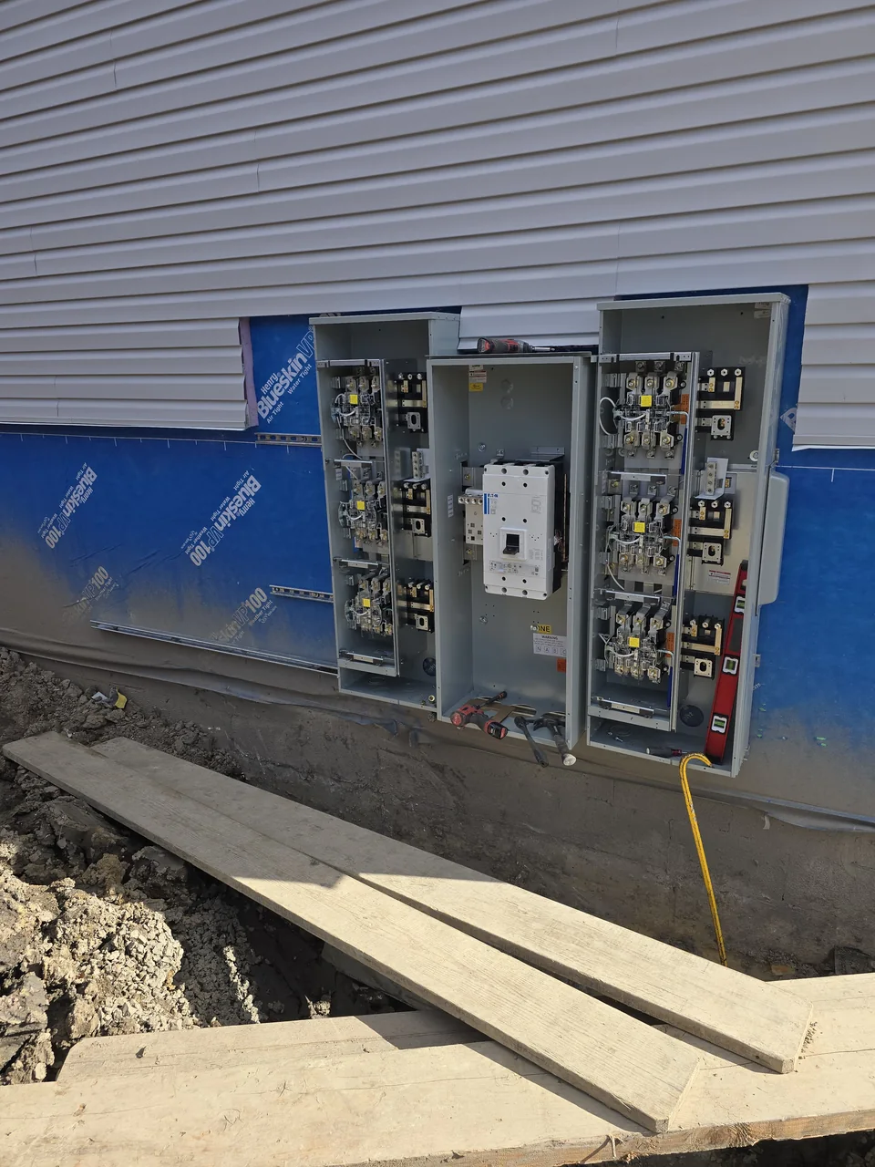 Open electrical equipment cabinets along the commercial building exterior