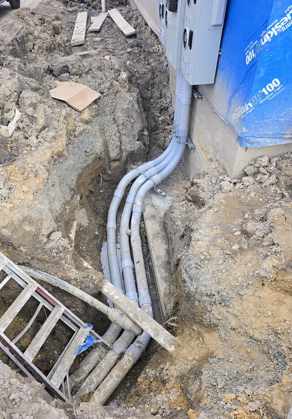 Conduits curving from the exterior electrical equipment toward a trench